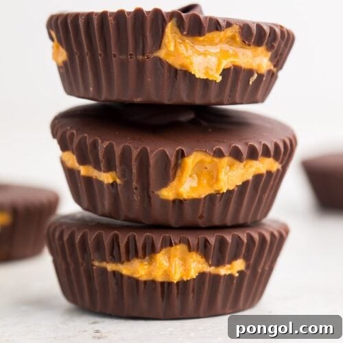 Zoomed out image of 3 perfect keto peanut butter cups stacked on a white background, highlighting their professional finish and inviting appearance.