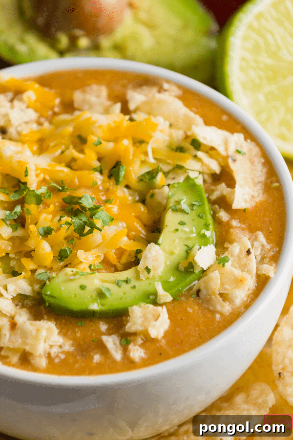 A half view of a bowl of keto chicken white chili with an avocado slice