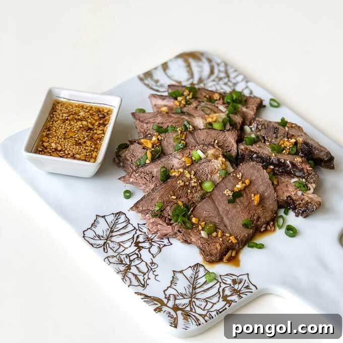 A marble platter with sesame beef and a square bowl of dipping sauce