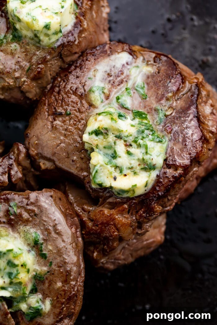 Overhead photo of a perfectly seared sous vide filet mignon in a pan with melting garlic herb butter.
