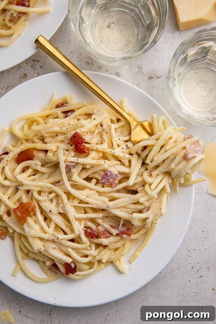 A white plate of keto carbonara with a golden fork
