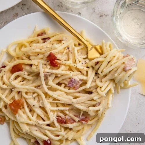 A white plate of keto carbonara with a golden fork