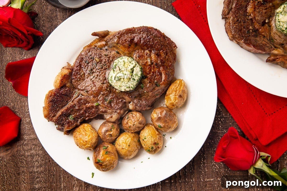 A whole bone-in ribeye steak, generously topped with garlic-herb butter, elegantly presented on a white plate alongside roasted potatoes, with a setting of red roses and a red napkin on a rustic wooden table.