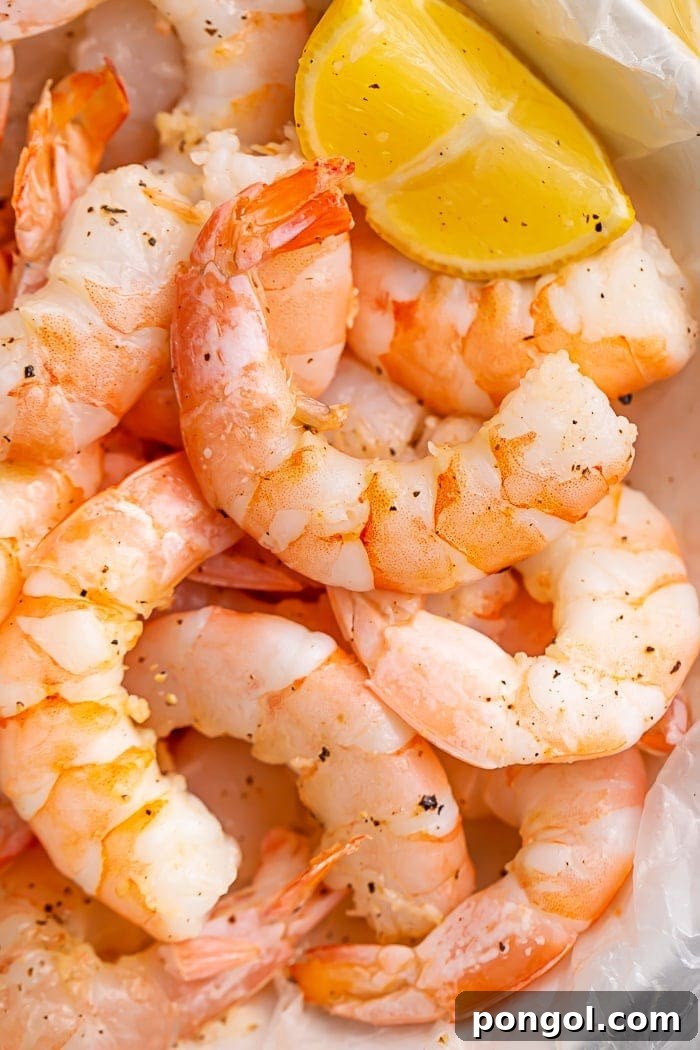Closeup of cooked shrimp in a bowl with a lemon wedge
