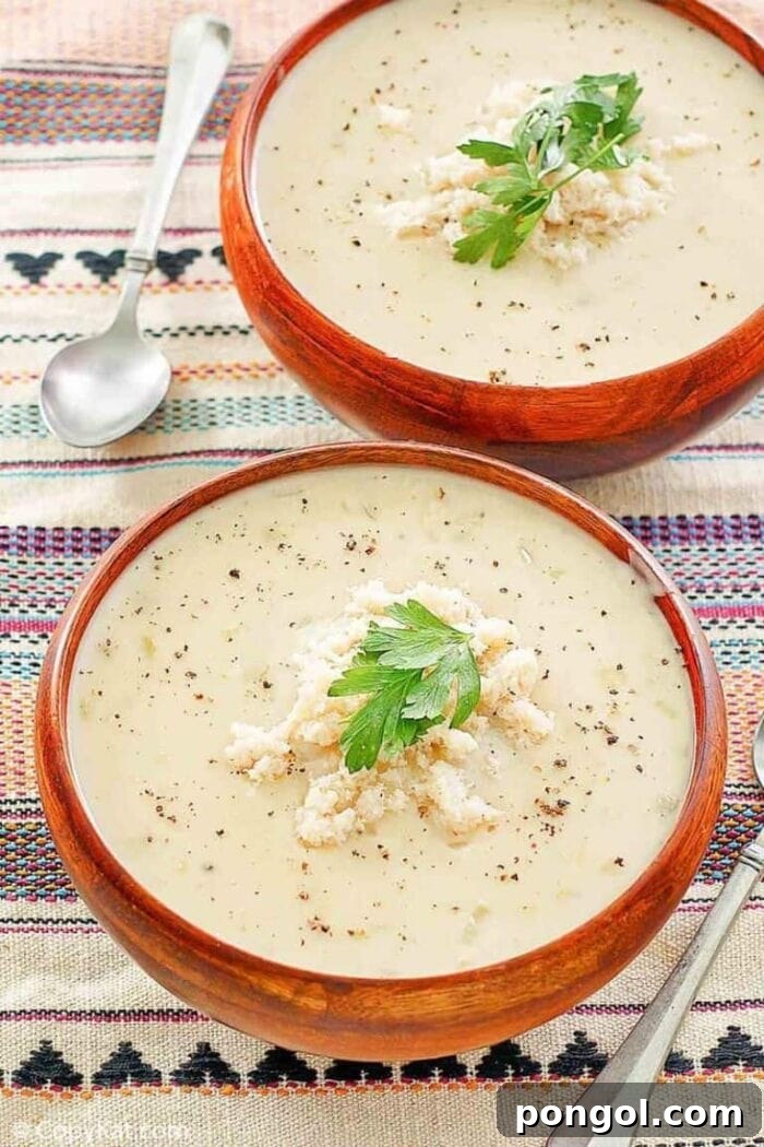 Two inviting red bowls of creamy crab bisque, elegantly placed on a subtly patterned background.