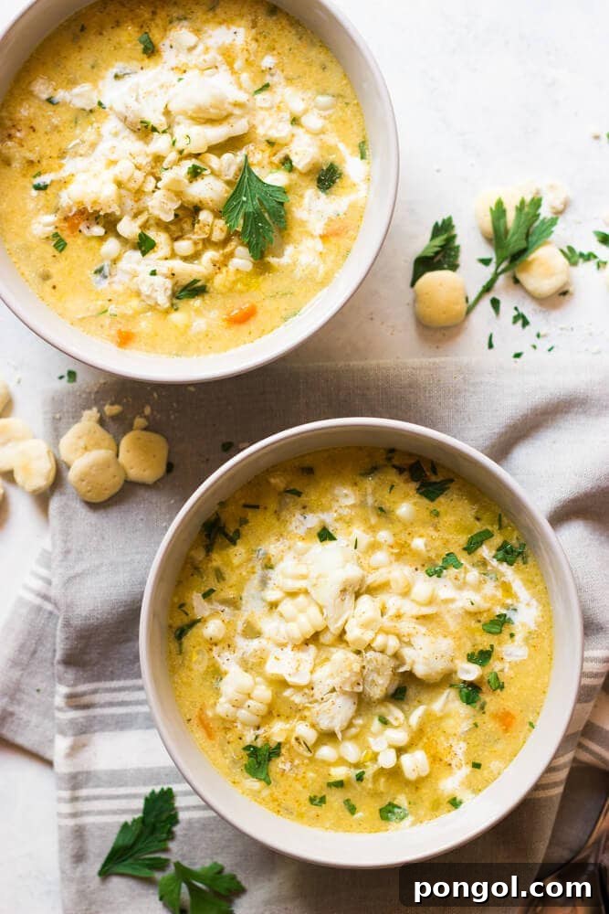 Two white bowls of comforting chowder on a light tablecloth, accompanied by oyster crackers.