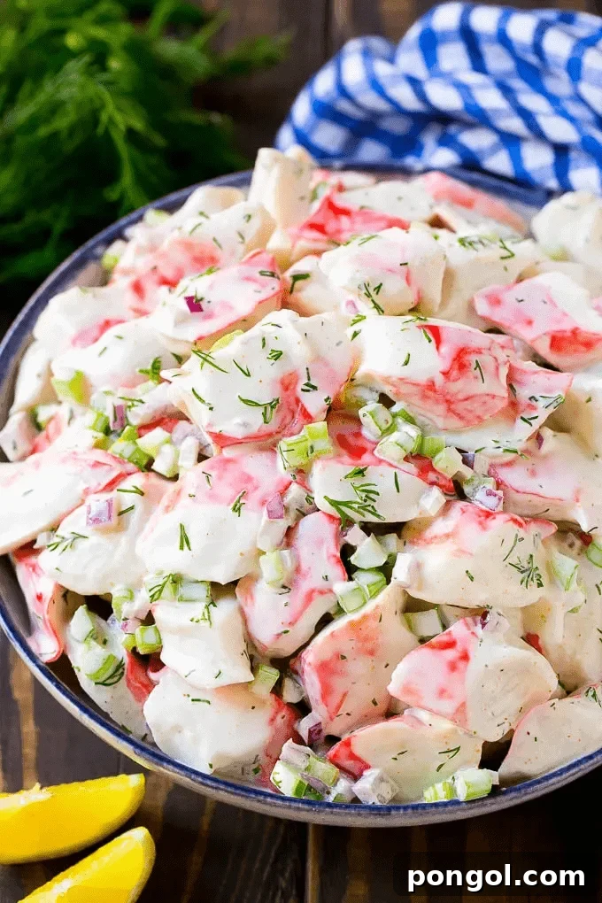 A large white bowl of refreshing crab salad, with a blue and white striped napkin adding a nautical touch in the background.