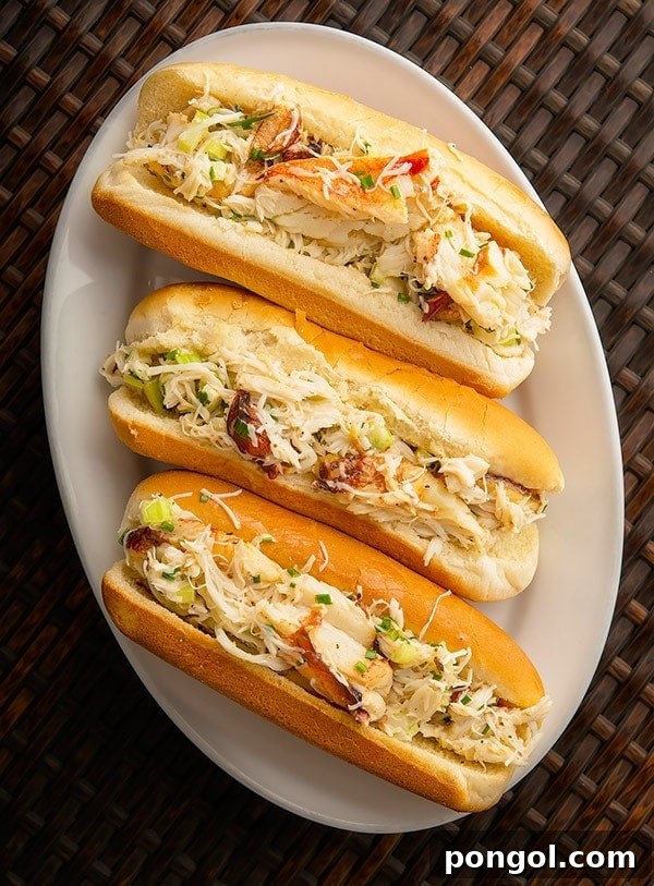 Three perfectly formed crab meat rolls, artfully angled on an oval white platter.