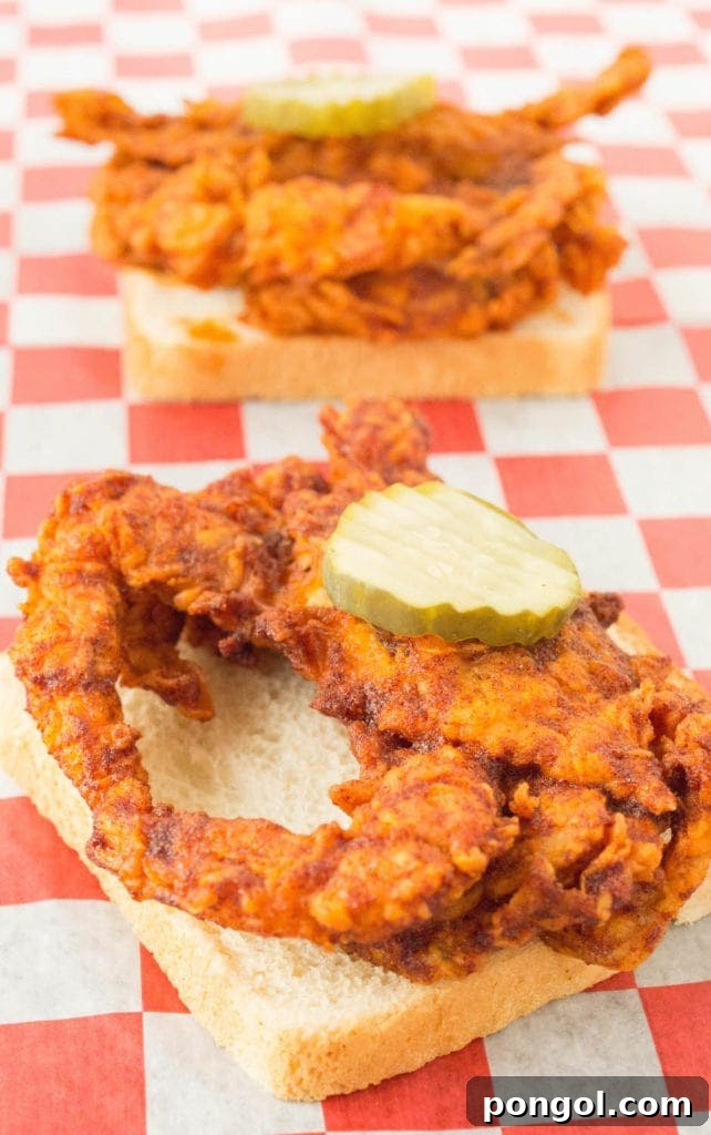 A golden-fried and seasoned soft shell crab resting on a slice of white bread, topped with a vibrant pickle.