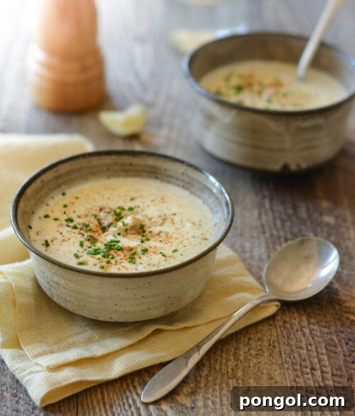 Two bowls of steaming crab soup on a rustic wooden table, one resting on a tan napkin.
