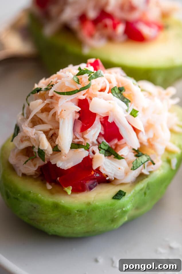Fresh avocado halves generously topped with savory crab meat and a vibrant garnish.