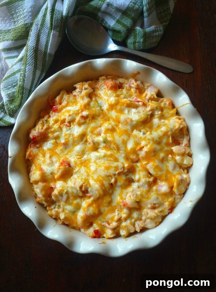 A scallop-edge white casserole dish filled with bubbling, cheesy crab casserole, golden and inviting.