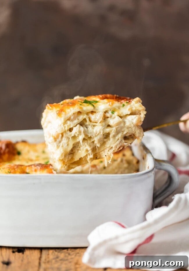 A square piece of cheesy seafood lasagna being lifted out of a white casserole dish with a spatula, revealing its layers.
