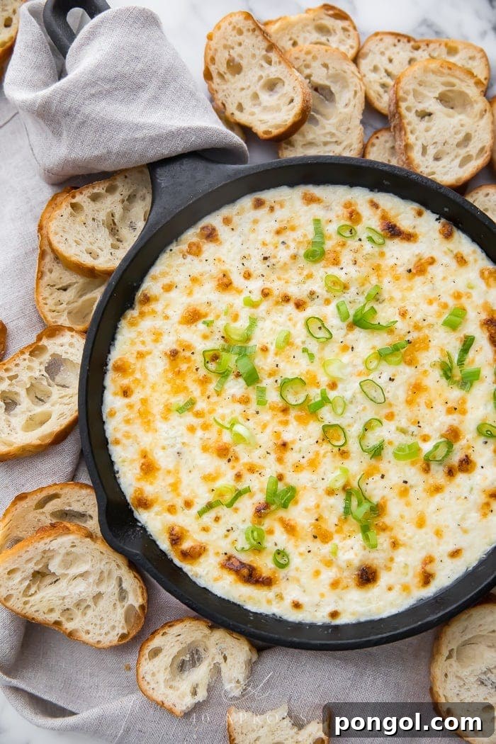 Bubbling hot crab dip in a cast iron skillet surrounded by golden crostini, ready for serving.