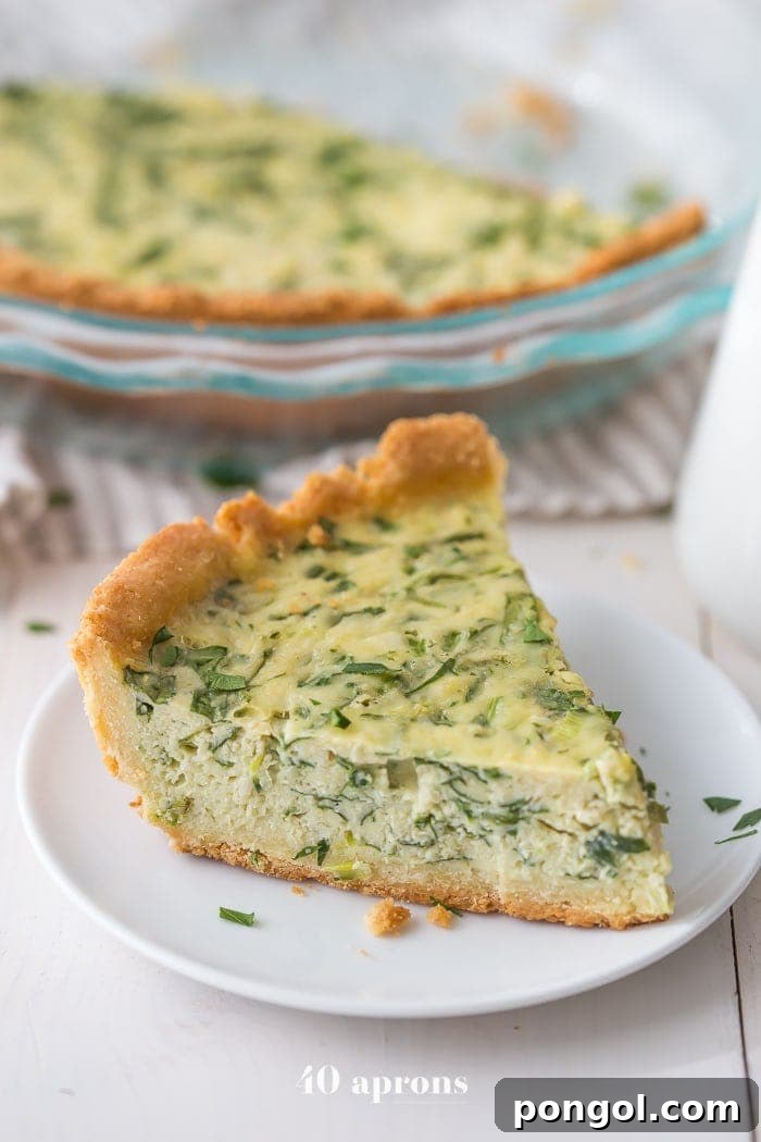 A perfectly baked wedge slice of paleo quiche with visible crab and spinach, presented on a white plate.