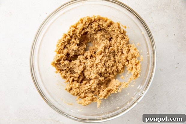 Ultimate Vegan Chocolate Chip Cookies 7 Liquid ingredients for vegan chocolate chip cookies, including vanilla and vegan milk, being added to the sugar and butter mixture.