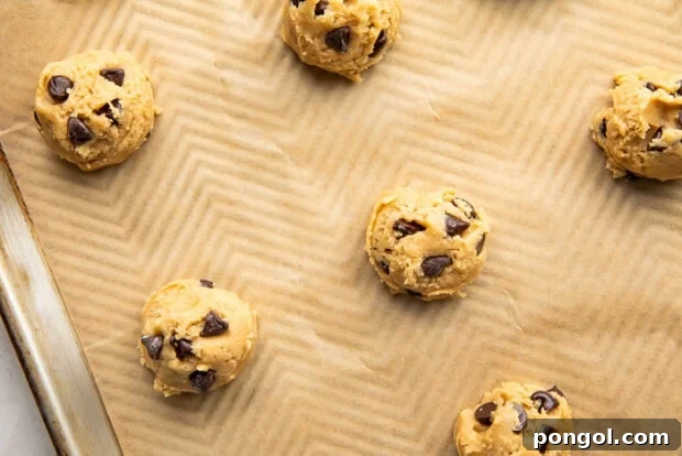 Ultimate Vegan Chocolate Chip Cookies 9 Portions of vegan cookie dough scooped onto a parchment-lined baking sheet, ready for baking.