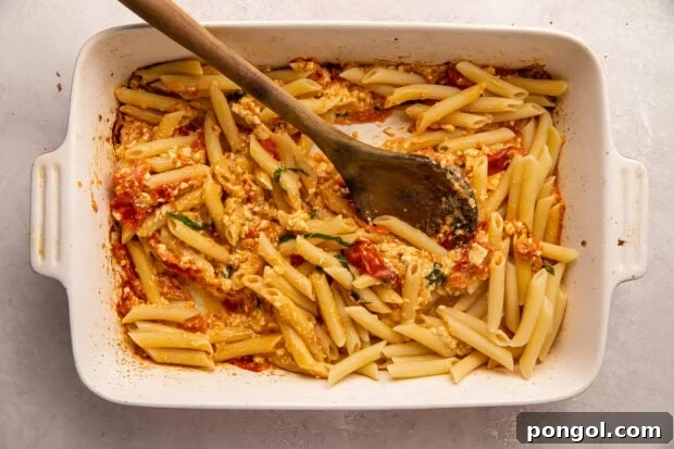 Baked feta pasta in a casserole dish, with the pasta fully incorporated into the sauce.