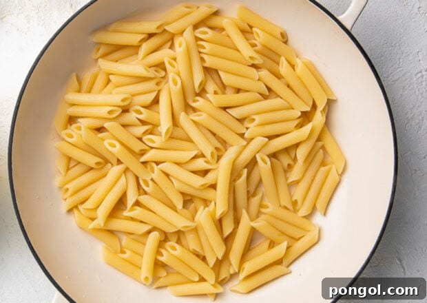 Penne pasta cooking in a pot of boiling water.