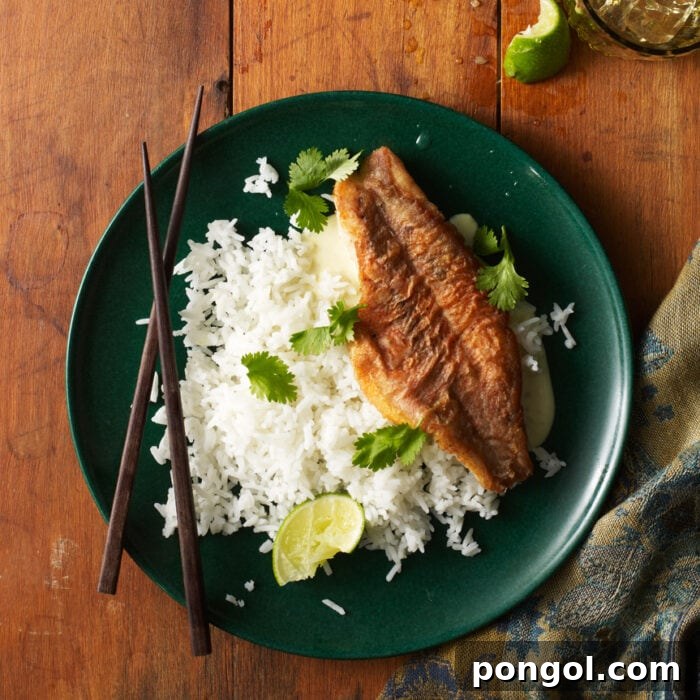 Orange roughy and white rice on a green plate with chopsticks, depicting an Asian-inspired meal presentation.