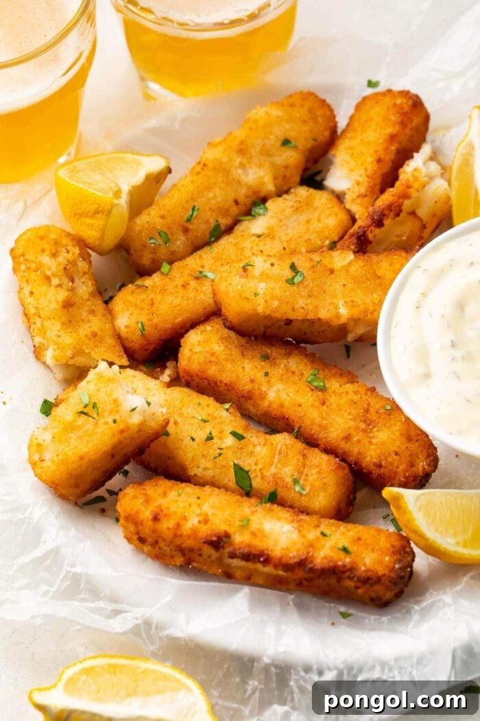 Air fried fish sticks on a white plate with dipping sauce, showcasing a golden, crispy texture