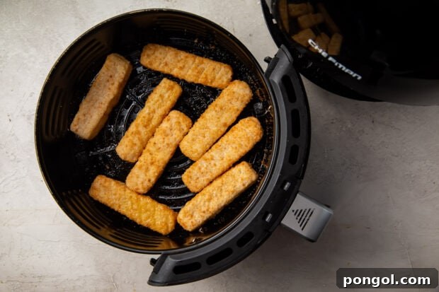 Frozen fish sticks in a black air fryer basket ready to be cooked