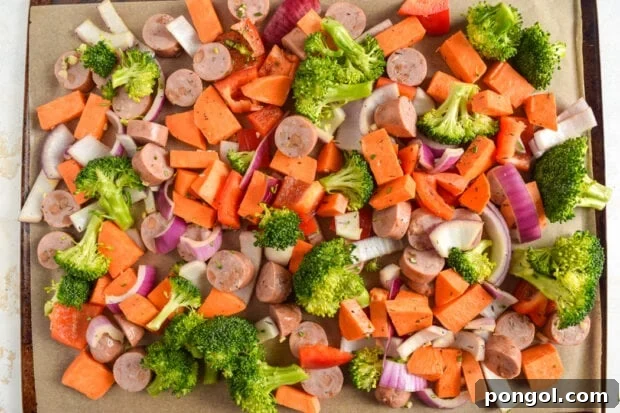 Sheet pan chicken sausage and vegetables roasting in the oven