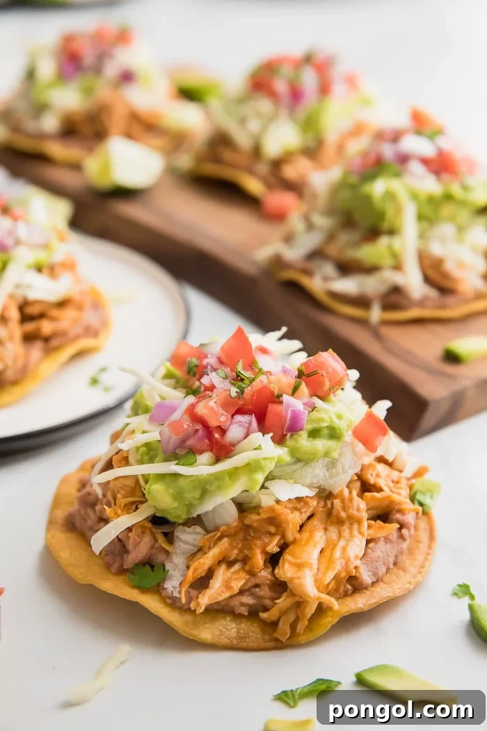 Healthy chicken tostadas on a plate in front of a pan of tostadas.