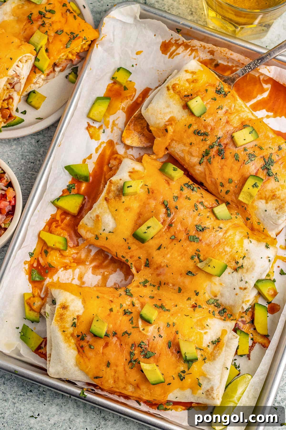 3 burritos suizos on a baking sheet lined with parchment paper.