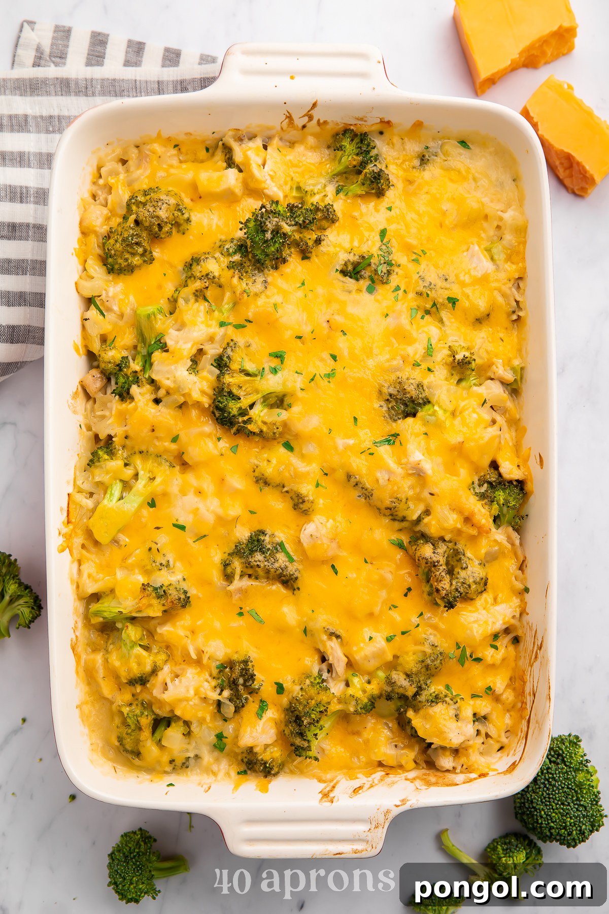 Overhead view of a white rectangular casserole dish full of cheesy chicken, broccoli, and rice.