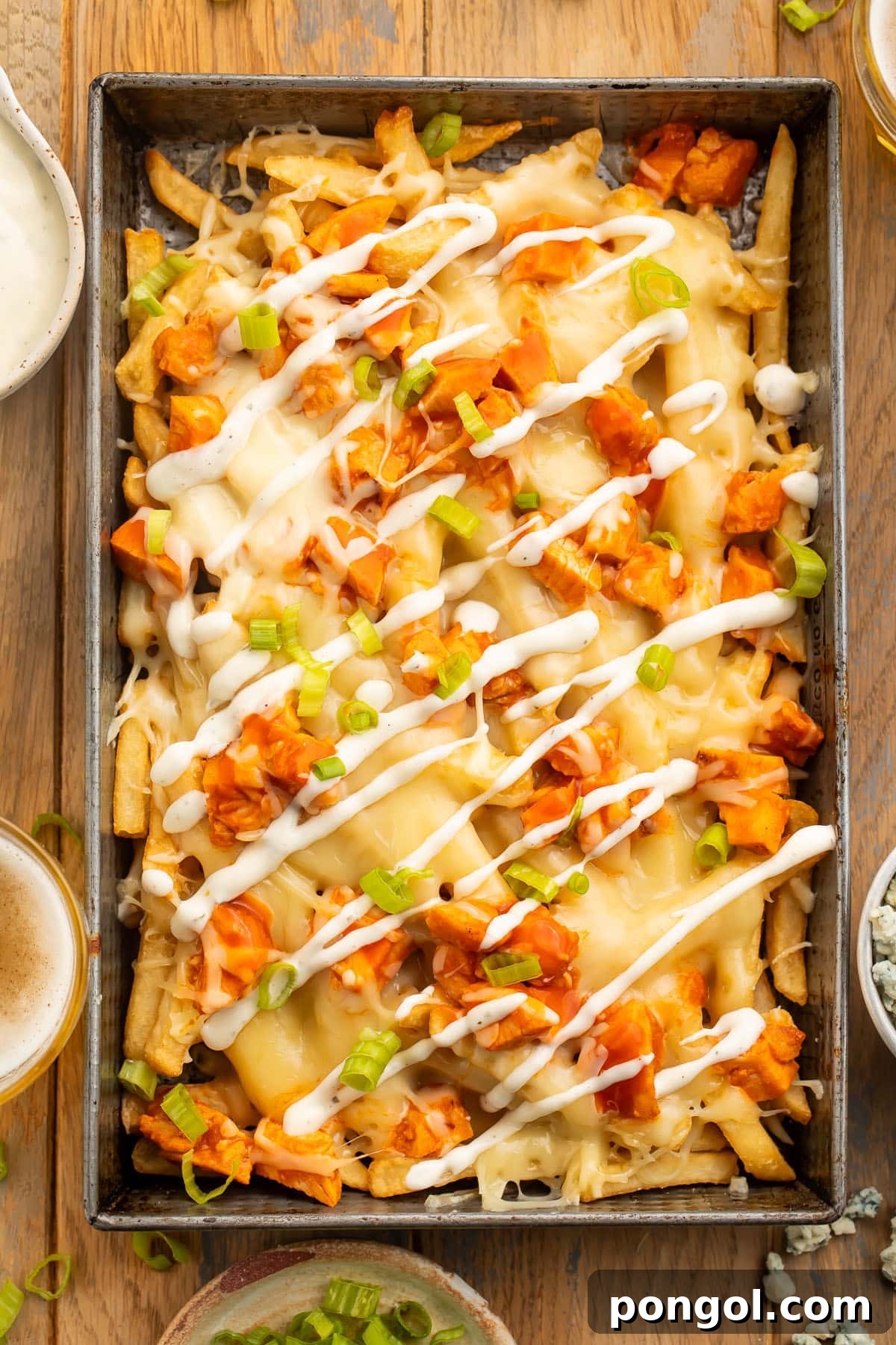 A large pan of fries topped with buffalo chicken, green onions, and ranch dressing.