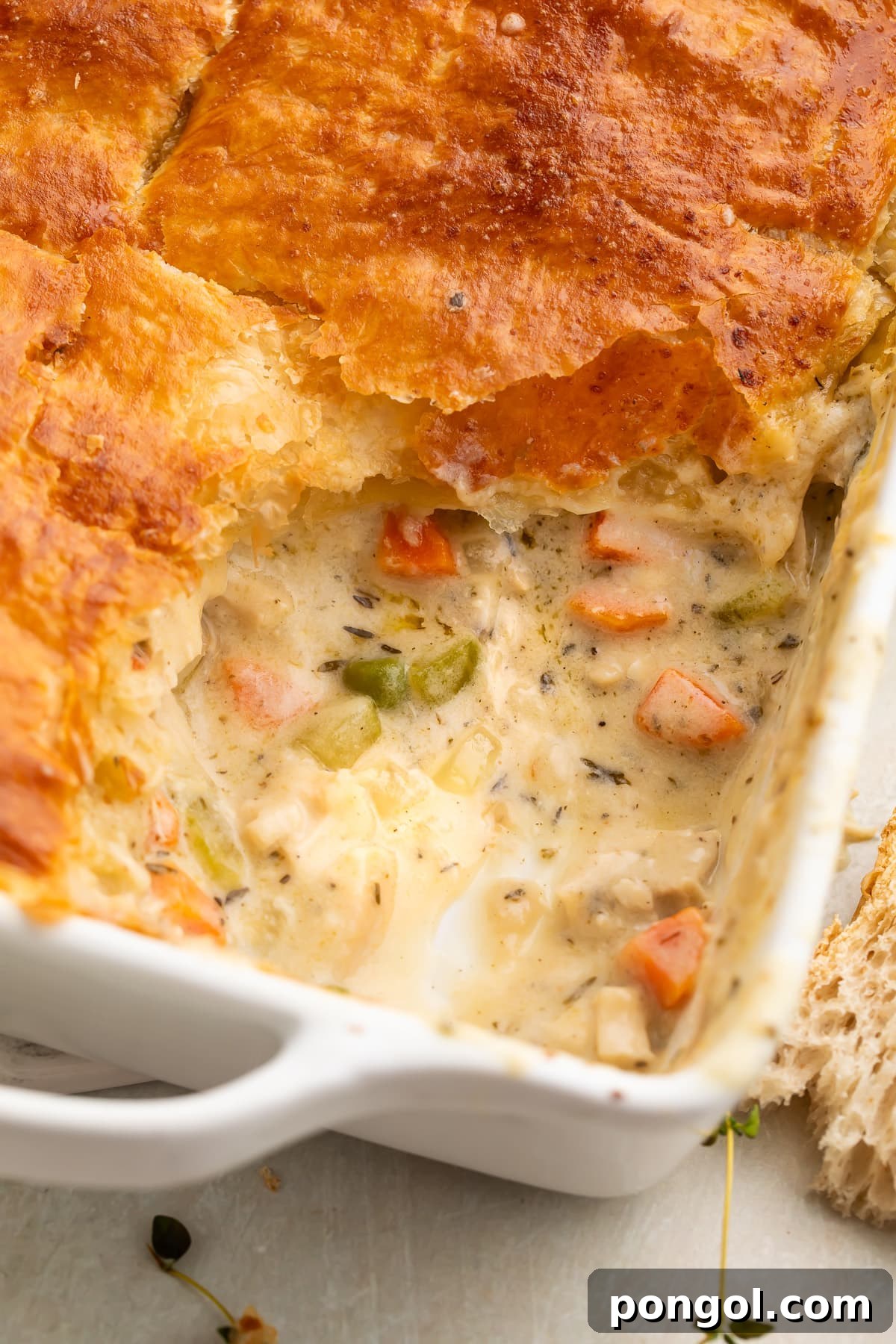 Chicken pot pie casserole in a square dish, with a corner scooped out to show some of the filling.