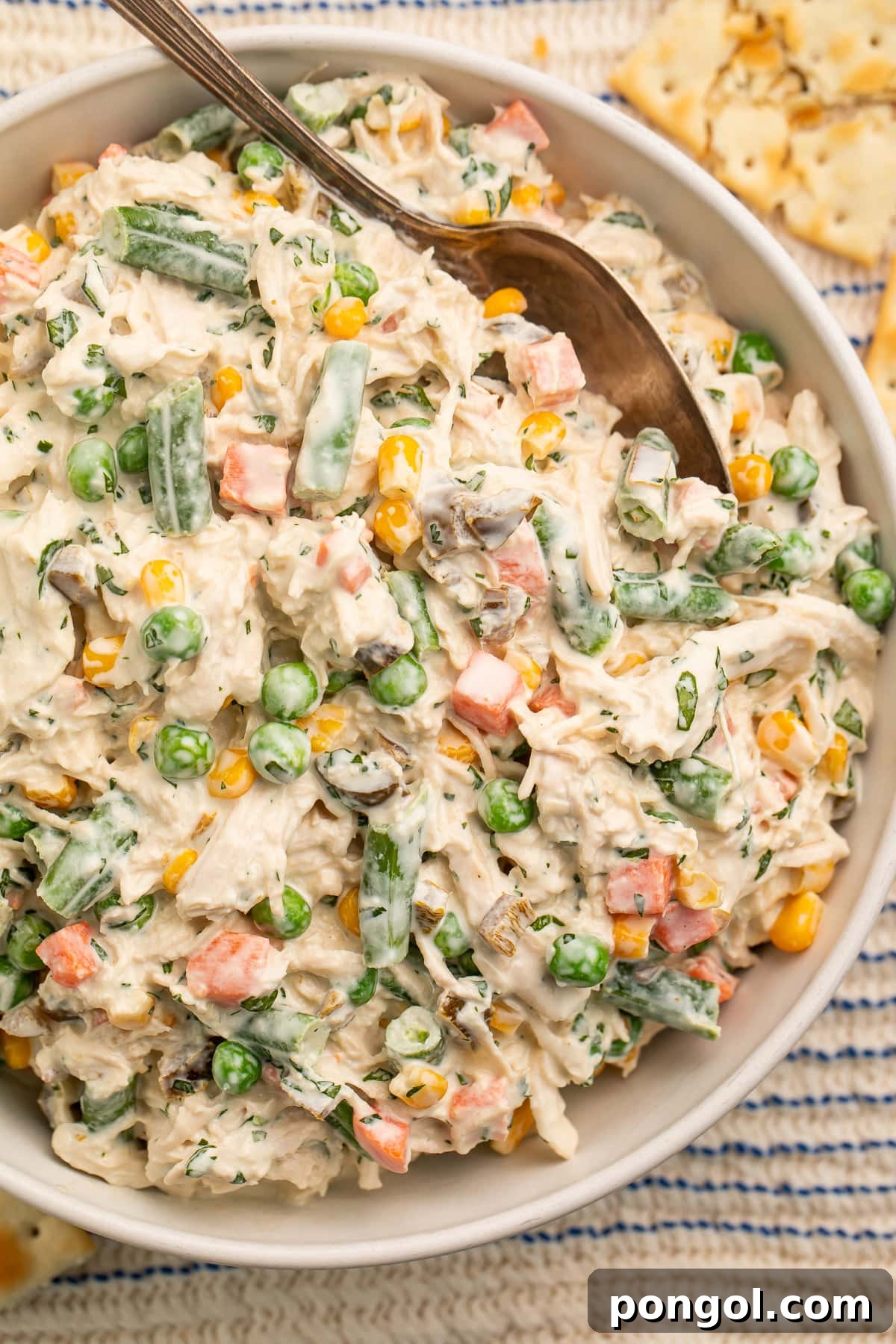 Top-down view of a bowl of Mexican chicken salad with shredded chicken, peas, carrots, and sour cream in a large bowl.