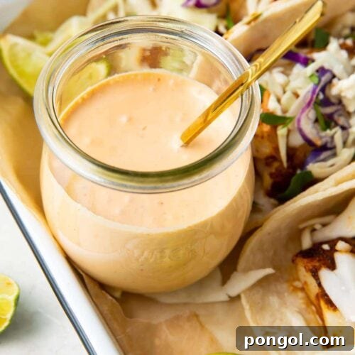 Fish taco sauce in a glass jar with a spoon, highlighting its creamy texture