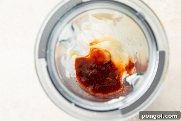 All ingredients for fish taco sauce gathered in a blender bowl, ready to be blended
