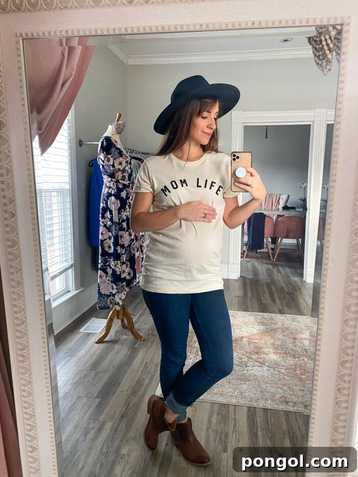 Pregnant woman taking a mirror selfie, showing off her baby bump and a comfortable tee.