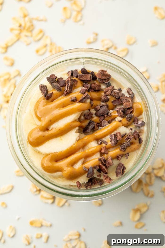 Peanut butter oatmeal topped with chocolate chips and a banana in a glass jar