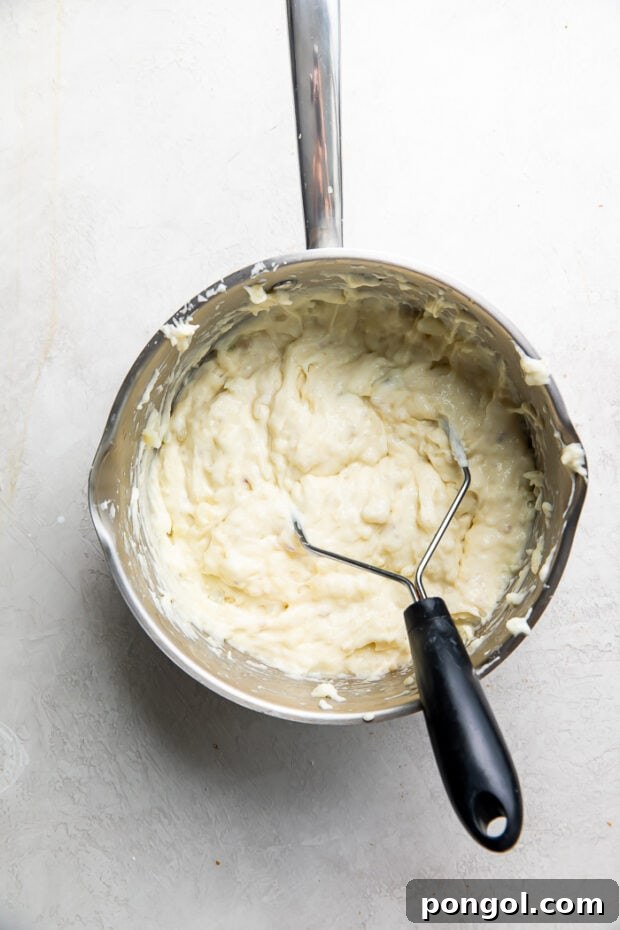Mashed potatoes being prepared with butter and milk