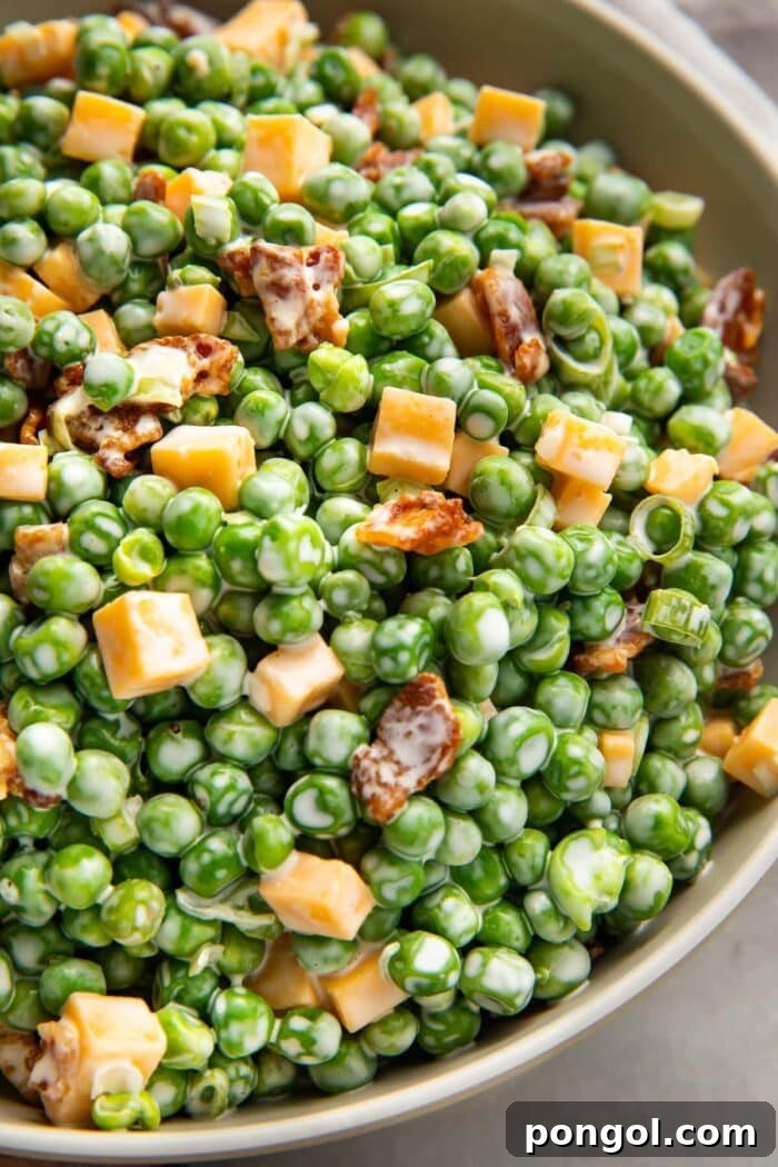 Pea salad with bacon, cheddar, and green onions in a large bowl