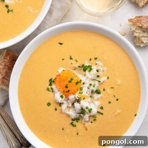 Overhead view of a white bowl of she crab soup with a glass of water at the top of the photo