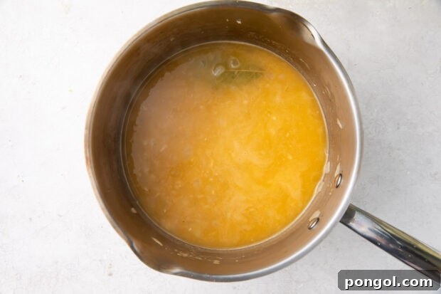 Fish stock with garlic, onion, and bay leaf in a large saucepan