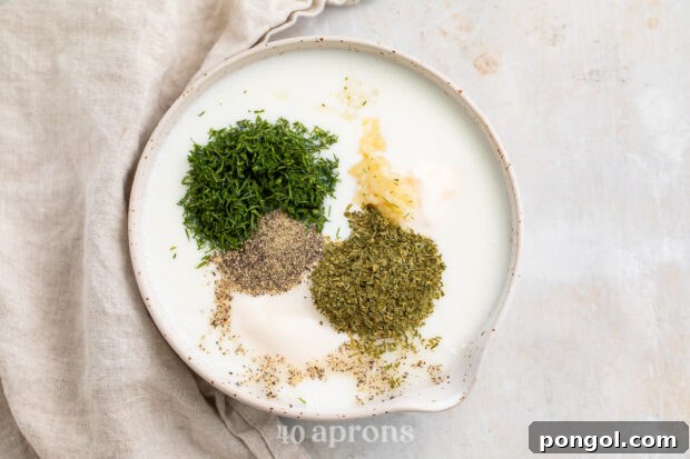 Overhead view of ranch dressing ingredients in a medium white mixing bowl on a neutral cloth napkin.