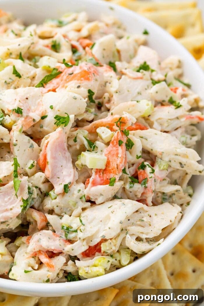 Crab salad in a bowl with an array of saltine crackers, showcasing a vibrant and fresh seafood dish ready to be enjoyed.