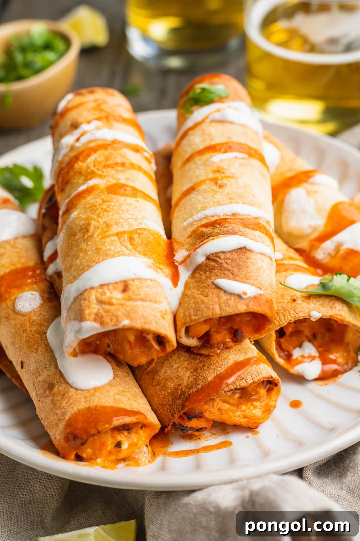 Mexican Chicken Extravaganza 19 A pyramid stack of 5 air fryer flautas topped with a drizzle of hot sauce and crema.