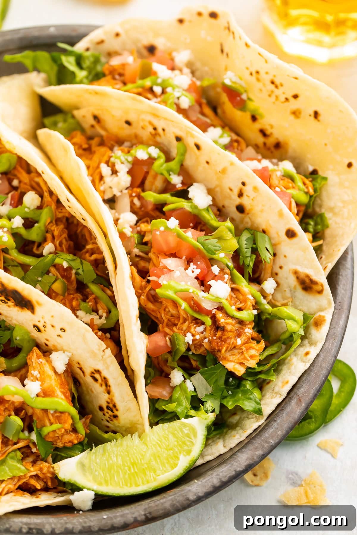 Mexican Chicken Extravaganza 22 Close-up look at an Instant Pot chicken taco with shredded chicken, tomatoes, lettuce, cilantro, cheese, and a lime wedge.