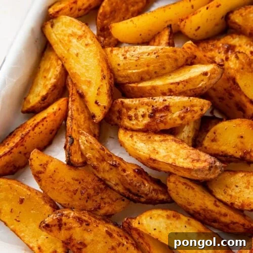 Air fryer potato wedges on a sheet pan next to a ramekin of ketchup