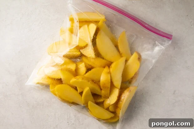 Raw potato wedges and olive oil in a plastic bag