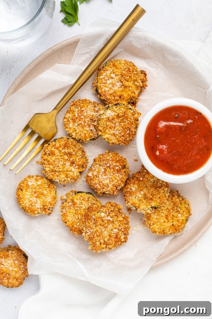 Air Fryer Zucchini Chips on a plate with a fork and a side of marinara sauce.