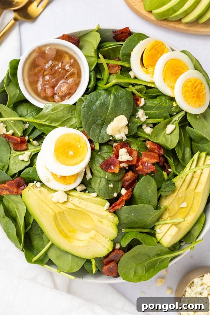 Spinach Salad overhead shot with a hot bacon dressing on the side.