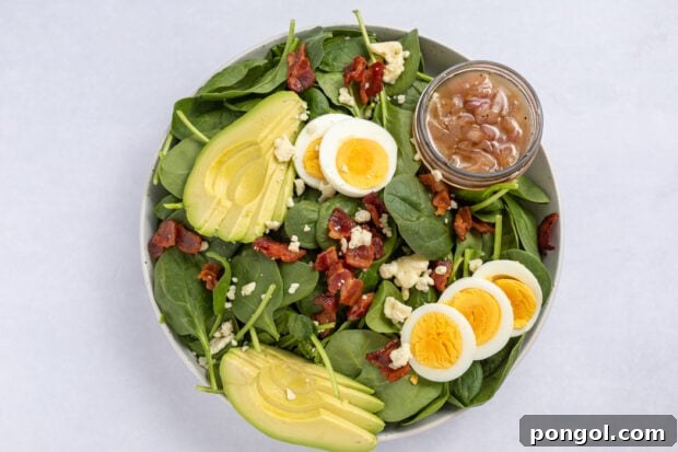 Assembling the spinach salad with dressing and toppings.